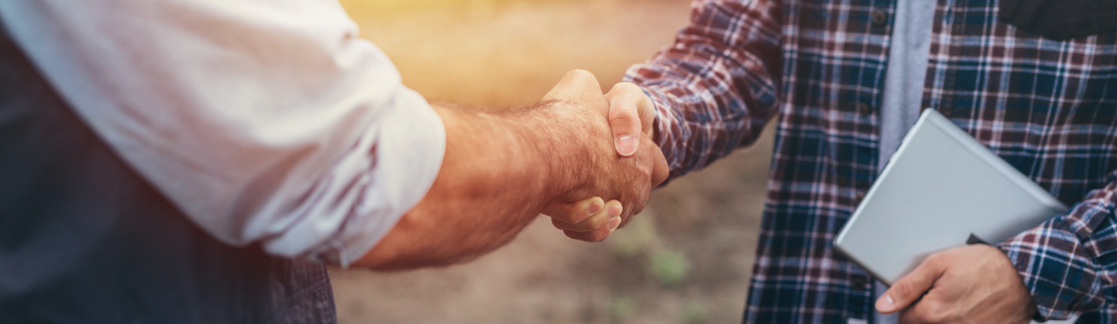 two farmers shaking hands in a field